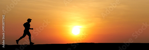 Silhouette of a runner against a setting sun, person running for health or fitness