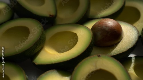 Fresh avocado slices and a whole avocado on a dark surface