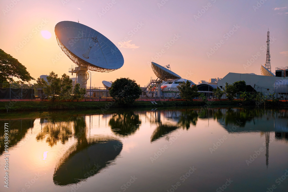 Obraz premium Large satellite dish antenna station by pond at dawn, Bangkok