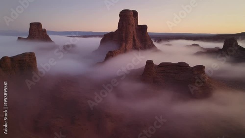 Misty sunrise over rugged rock formations in a desert landscape with fog rolling in