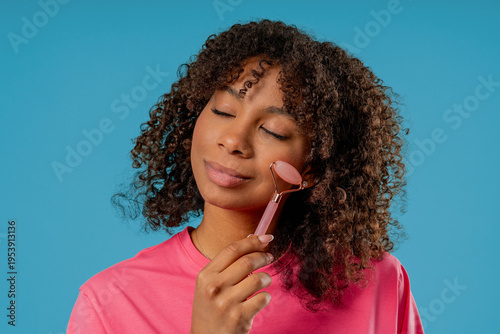 Tableau sur toile Charming African Woman Doing Face Massage With Rose Quartz Stone Roller Firmer