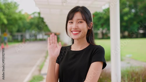 Smiling Wave: A warm and inviting portrait of a young woman extending a friendly wave with genuine smile and eyes full of joy. Capturing the essence of approachability.