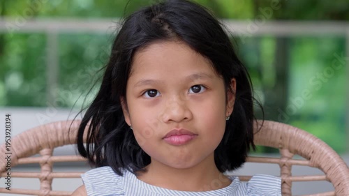 Childhood Gaze: A captivating portrait of a young girl, radiating innocence and curiosity, as she sits, her eyes meeting the viewer's with a thoughtful expression.