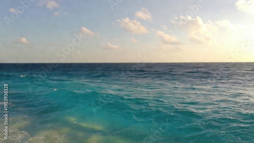 Calm turquoise ocean horizon at sunset with gentle waves for seascape background and coastal wallpaper design