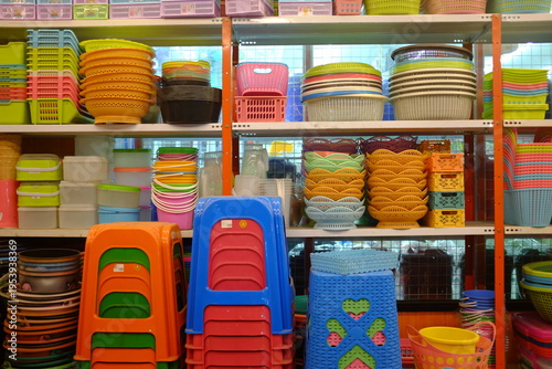 Plastic containers and colorful household items on store shelves. Kitchen plastic bowls, storage boxes, and baskets in a retail display.