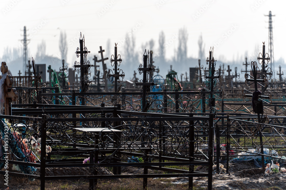Fototapeta premium A wide shot of an old, crowded Orthodox Christianity cemetery with numerous black metal crosses and fences under a hazy sky.