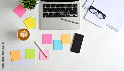 Creative workspace seen from above with laptop, glasses, coffee, smartphone, colored pencils and sticky notes on white desk, brainstorming, planning, vibrant productivity and idea generation concept.