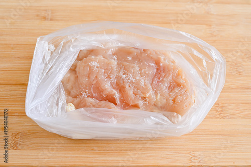 ポリ袋に入れた鶏胸肉に塩をふる