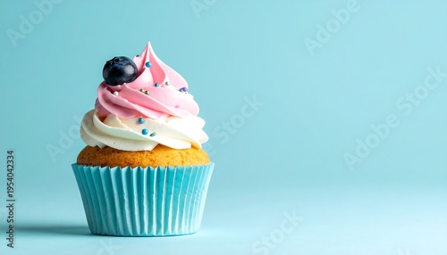 Delicious cupcake with pink frosting and blueberry.