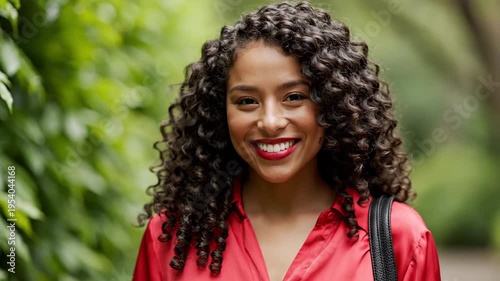 Smiling woman with curly hair posing outdoors in natural lighting