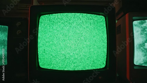Stack of old television sets displaying static and colored screens