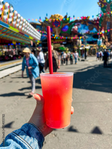 Red orange slushy iced beverage handheld at local colorful festival fair