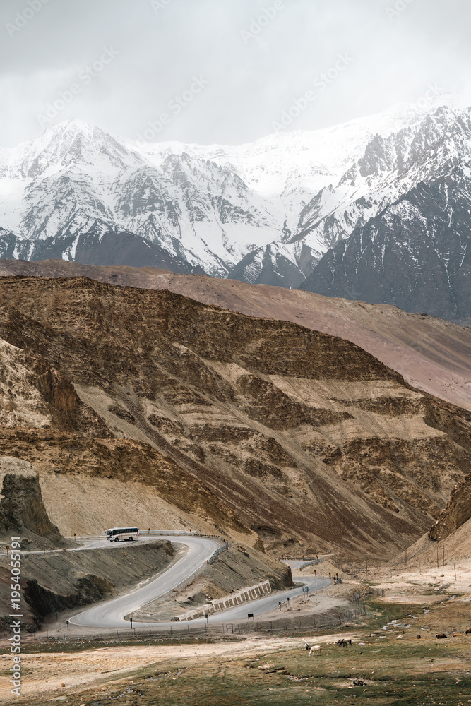 Obraz premium Winding road mountain snow landscape travel adventure nature scenic remote transportation. winding road curves through remote mountain landscape with snow capped peaks background evoking sense