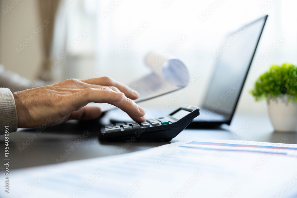 Obraz premium Hand pressing buttons on a calculator, processing financial data, managing budget in an office environment