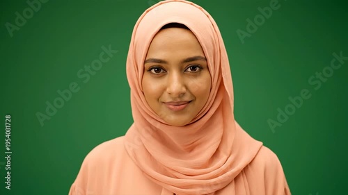 Woman wearing headscarf smiling on green background
