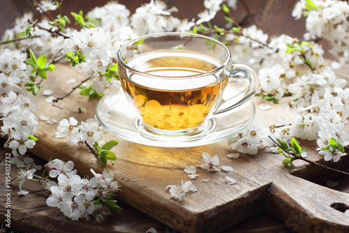 Blooming spring tree herbal blossom tea in a glass cup with flowers on wooden rustic background, closeup, spring floral drink, natural medicine and naturopathy concept