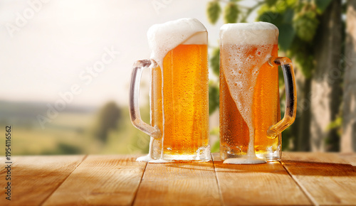Cold beer mugs placed on rustic wooden table with softly blurred background of green garden and hop plants. Refreshing summer atmosphere and traditional brewing culture.