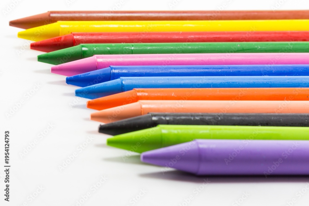 Fototapeta premium Colorful Wax Crayons Arranged in a Row on White Background