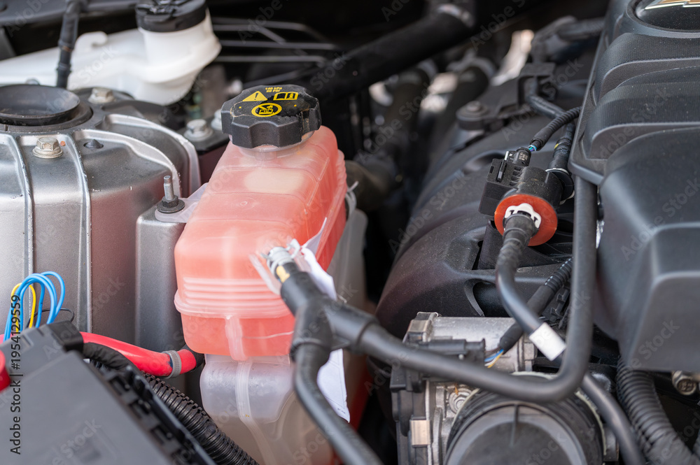Fototapeta premium Close-up of a car engine coolant expansion tank filled with pink antifreeze. Automotive cooling system maintenance, vehicle service, and engine temperature control concept