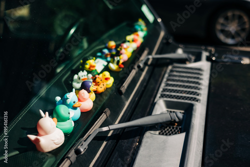 Fotografie Colorful rubber ducks placed on the windshield of a parked car during a sunny da