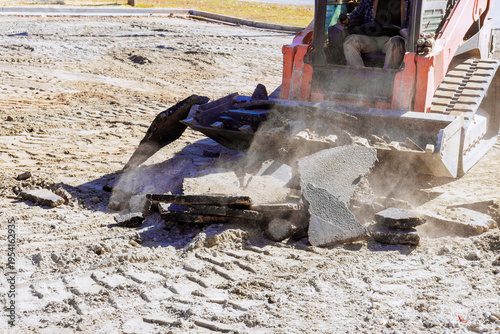 Construction equipment breaking concrete on work site uses skid steer