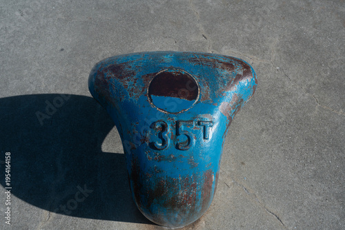 Primer plano de una bita de amarre marina de metal azul desgastada con la marca 