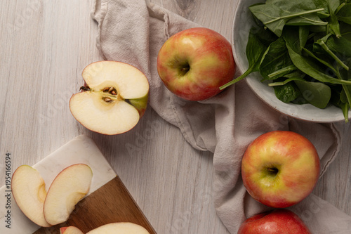 Top view of sliced apples and fresh ingredients arranged on a light surface, healthy cooking concept.
