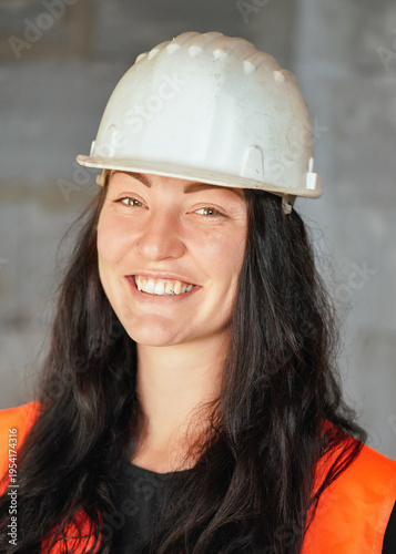 Young woman construction worker in protective helmet, closeup detail to her smiling face