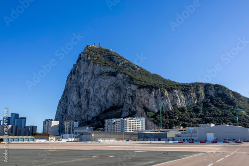 View of the Rock of Gibraltar and surrounding buildings against a clear blue sky during daylight hours
