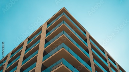 A modern high-rise building with balconies against a clear blue sky