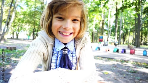 Little girl sitting at the table in the park and smiling.