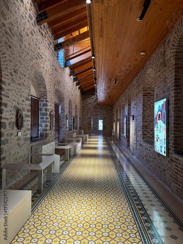 An atmospheric interior of a historic bathhouse featuring stone architecture, traditional bathing basins, and decorative patterned tiles. The combination of textured stone walls, warm wooden elements,