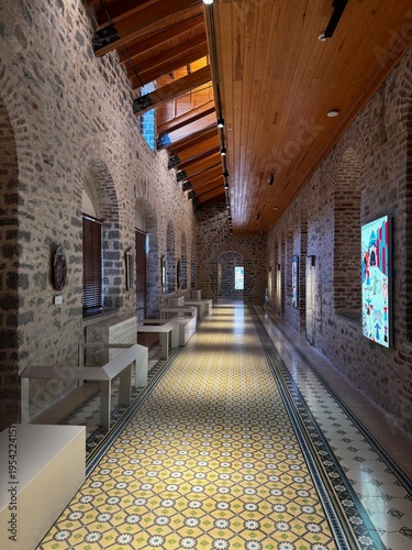 An atmospheric interior of a historic bathhouse featuring stone architecture, traditional bathing basins, and decorative patterned tiles. The combination of textured stone walls, warm wooden elements,