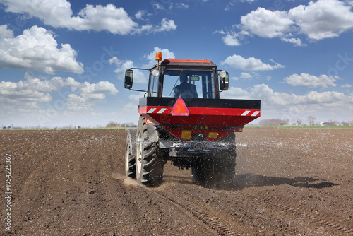 Spreading mineral fertilizer. Farmer with agricultural machinery fertilizing agricultural field in spring time.