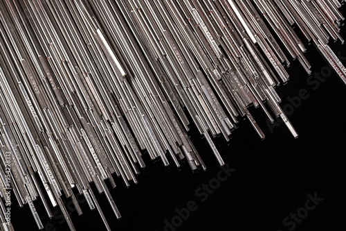 Fotografie Silver welding rods on black reflective surface
