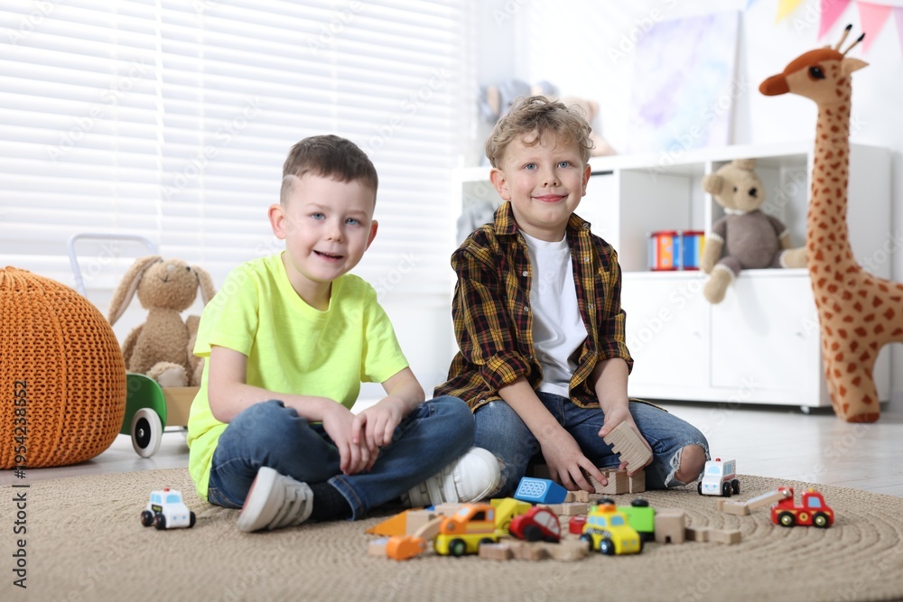 Fototapeta premium Cute little boys playing with toys on floor indoors