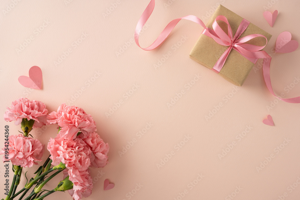 Naklejka premium Happy Mother's Day flat lay featuring pink carnations, a wrapped gift box tied with ribbon and scattered paper hearts conveying love and appreciation for mom