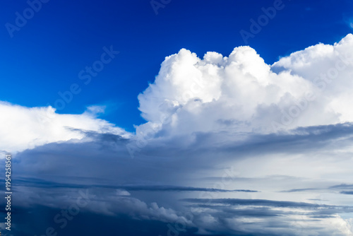 Majestic white cumulus clouds towering into a vibrant deep blue sky during a bright sunny day, showcasing the beauty of nature and the expansive atmosphere in a peaceful and serene landscape. 