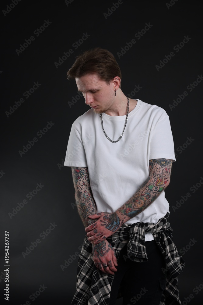 Fototapeta premium Young man with tattoos in stylish clothes on black background