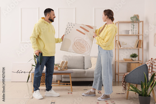 Young couple hanging painti...
