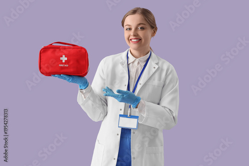 Female doctor showing first aid kit on lilac background