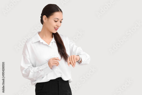 Young Asian businesswoman checking time on white background