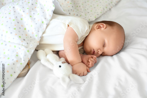 Photos Cute little baby with toy bunny and blanket sleeping on bed, top view