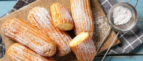 Board with tasty eclairs, s...