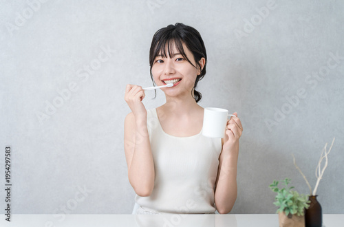 Konstfotografi A young Asian woman brushing her teeth (toothbrushing, oral care, dental care)
