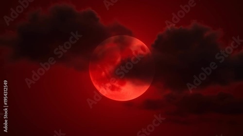 Spooky big red full moon, also known as a blood moon, rising in a dark night sky. Dark, ominous clouds slowly pass in front of it