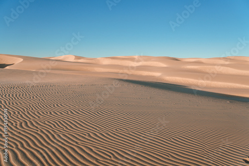 Golden sands ripple under clear blue sky