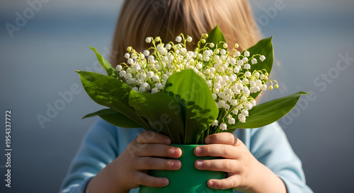 Child holding lily of valley flowers in green pot