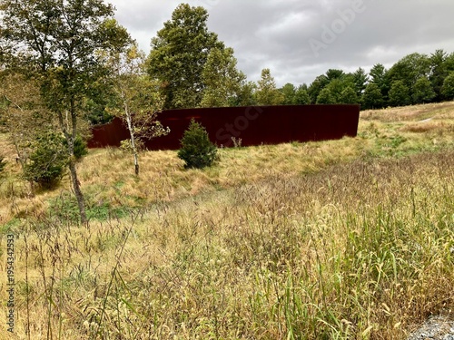 Rust colored metal wall structure in natural meadow landscape