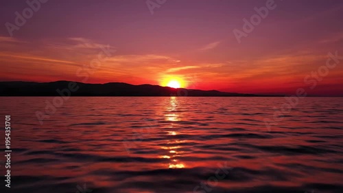 Vibrant sunset reflection over calm water surface with dramatic sky